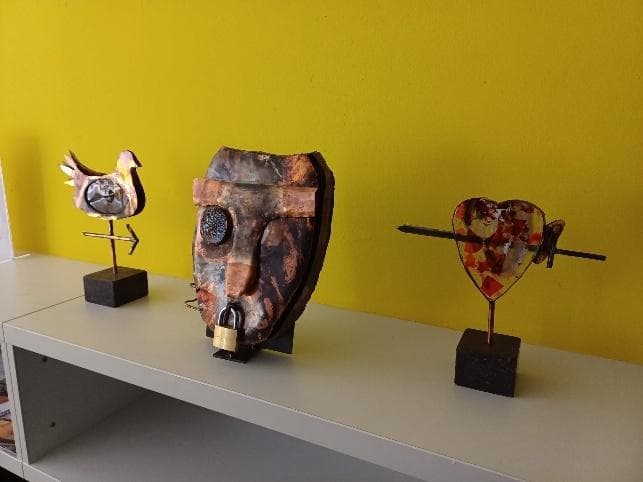 Drie beelden naast elkaar tegen een gele muur bij Kunst in de Bieb